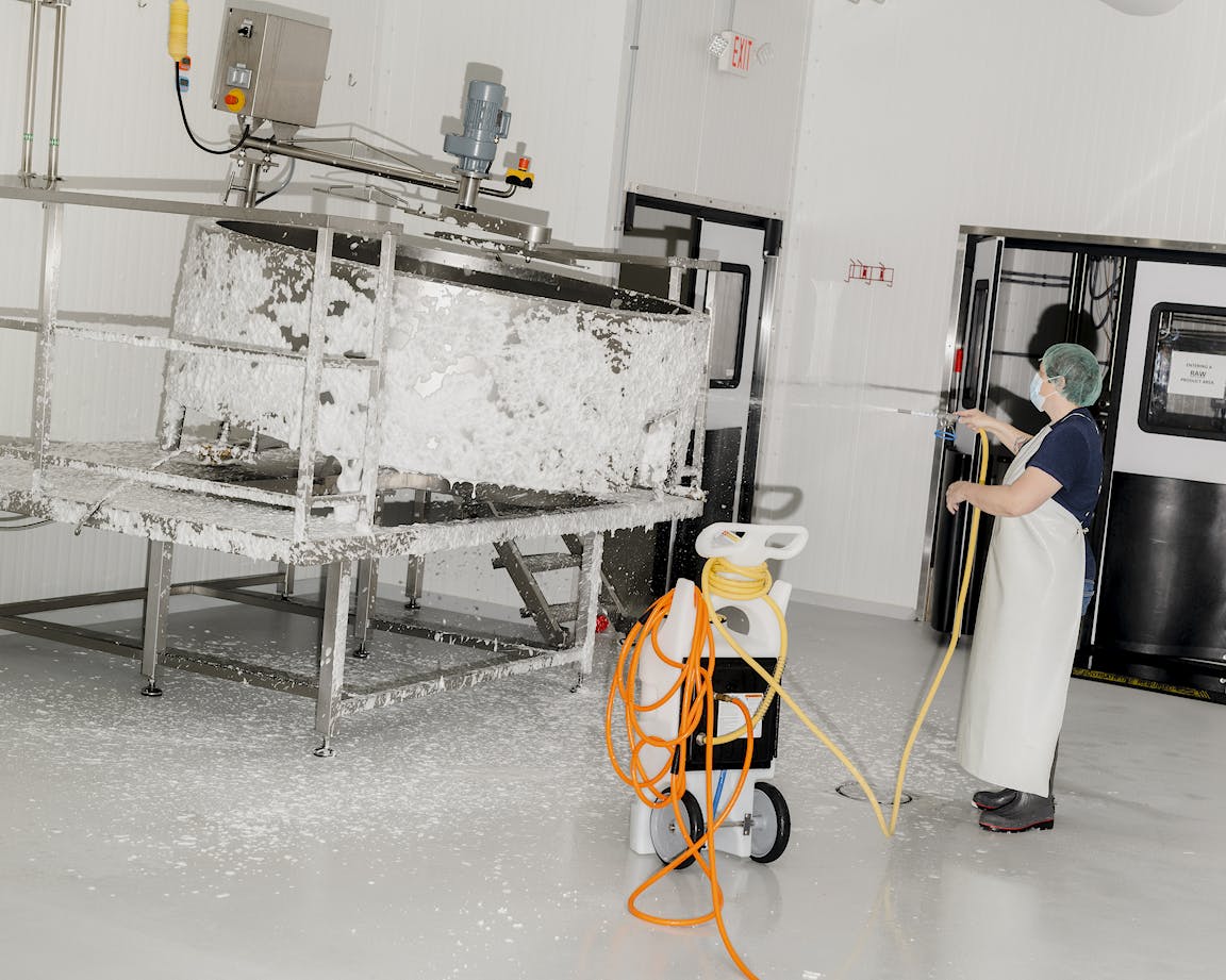A person rinses off industrial equipment.